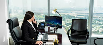 A woman is seated at a sleek executive desk in a Servcorp Serviced Office, at Emirates Towers, Dubai